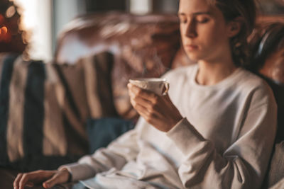 Portrait of candid authentic smiling handsome boy teenager using mobile phone at xmas home interior