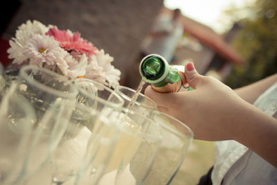 Cropped hand of woman pouring champagne in flute on table at wedding