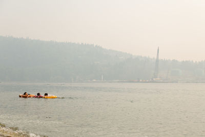 People on boat in river against sky