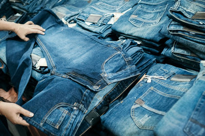 Cropped hands of person buying jeans at store