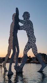 Silhouette men in water against clear sky