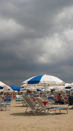 Lounge chairs and parasols on beach against sky