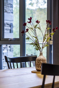 Flower vase on table by window at home