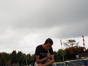 Young man looking at camera against sky