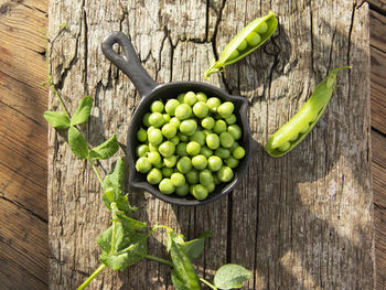 Fresh green peas young in bowl, on wood table, top view, seeds, pods, sprouts.