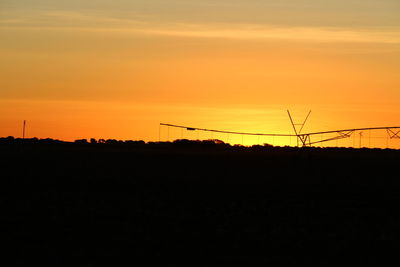 Silhouette electricity pylon against sky during sunset