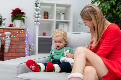 Portrait of siblings sitting on sofa at home