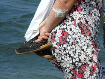 Low section of woman with umbrella on sea shore