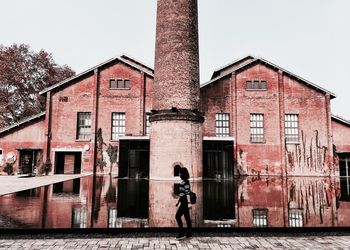 Full length of man climbing on wall in city against sky