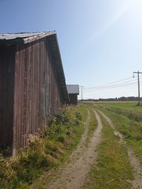 Road amidst field against clear sky