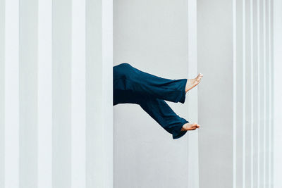 Woman feet floating against the building white wall