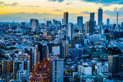 Aerial view of illuminated buildings in city against sky