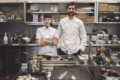 Portrait of smiling male and female chefs in commercial kitchen