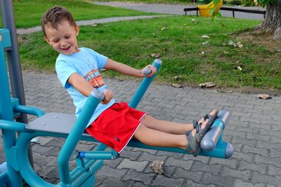 Full length of happy boy enjoying on play equipment at park