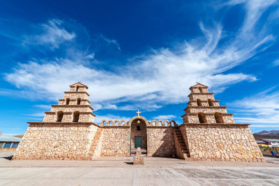 Tourists on top of historic building against cloudy sky