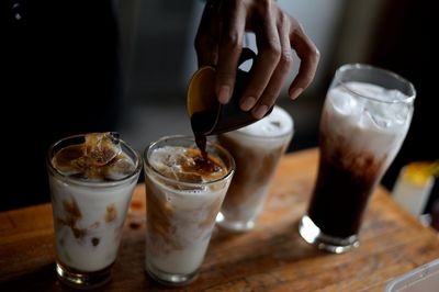 Close-up of hand holding drink on table