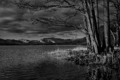 Scenic view of lake and mountains against cloudy sky