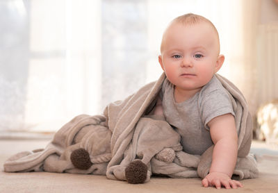 Portrait of cute baby boy with blanket sitting at home