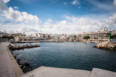 Sea by buildings in city against sky