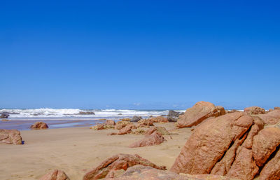 Scenic view of beach against clear blue sky