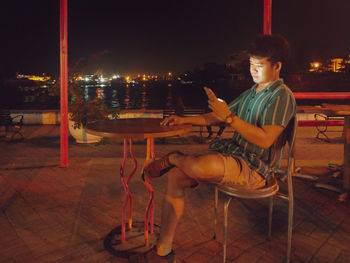 Young man using phone while sitting on table