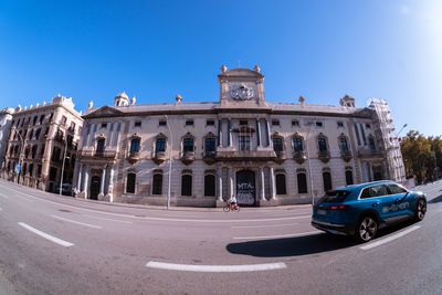 Cars on street against buildings in city against clear blue sky