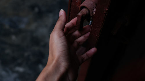 Close-up of person hand touching metallic door