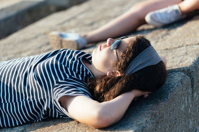 Teenage girl wearing sunglasses lying on retaining wall