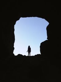 Silhouette woman standing on rock formation against clear sky