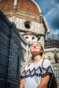 Low angle view of woman looking up in city