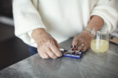 Midsection of senior woman taking pills at home