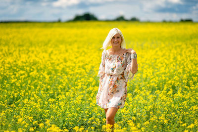 Portrait of woman standing amidst yellow flowers on field