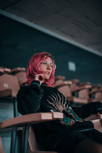 Low angle view of woman with dyed hair sitting on chair