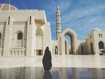Full length rear view of silhouette woman visiting mosque against sky