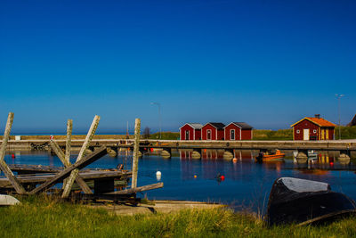 Houses by lake against clear blue sky