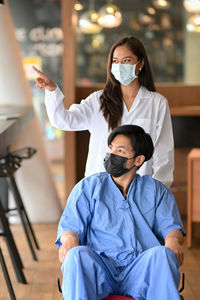Doctor wearing mask pointing away with patient