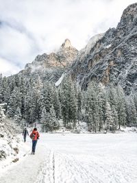 Rear view of people walking on snow covered field against mountain