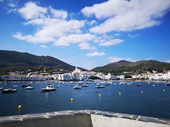 Sailboats on sea by city against sky