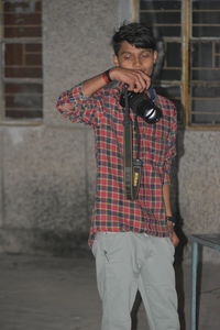 Portrait of young man standing against wall