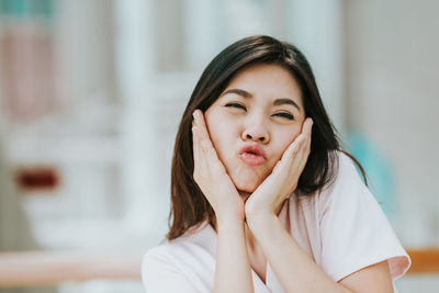 Close-up portrait of young woman puckering lips at home