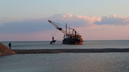 Ship in sea against sky during sunset