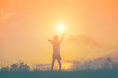 Boy standing on land against sky during sunset