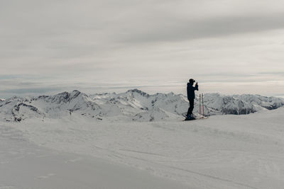 Man standing on snowcapped mountain against sky