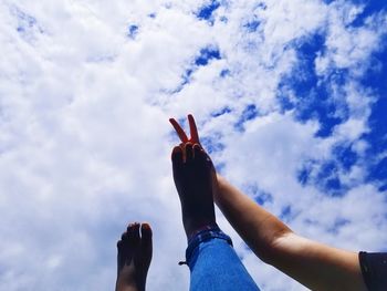 Low angle view of people on hands against sky