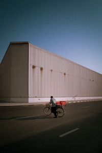 Man riding bicycle in city against clear sky