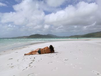 Young woman on beach against sky