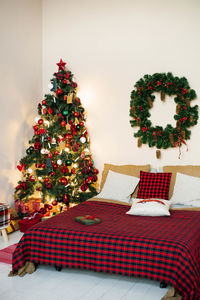 Bedroom with a bed and a christmas tree in red and light colors.