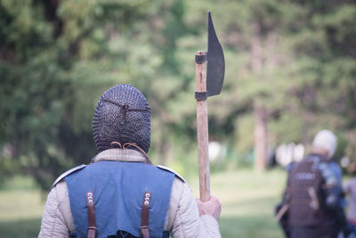 Knight in armor with weapon standing against trees