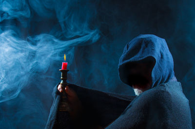 Close-up of man holding burning candle