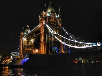 Illuminated suspension bridge over river at night